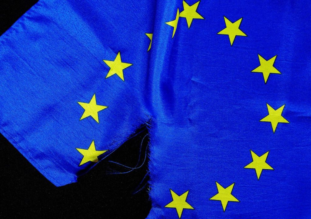 Foto einer zerissenen EU-Flagge als Symbol des umstrittenen EU-Lieferkettengesetz