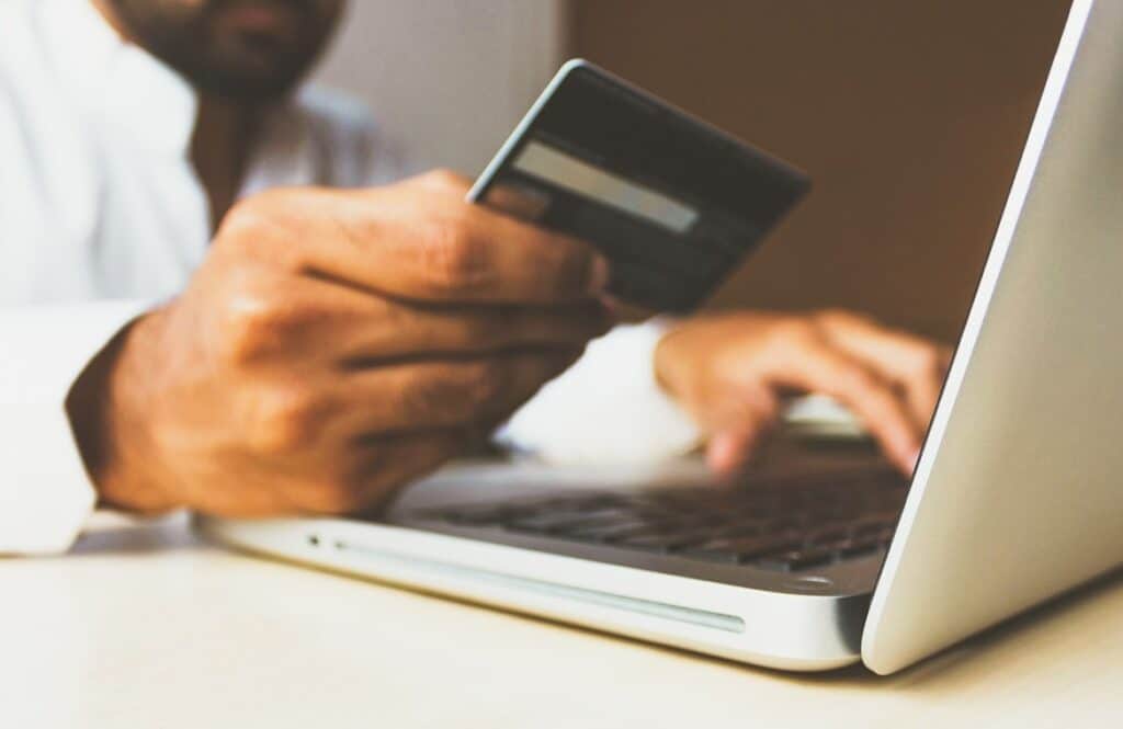 Online-Shopper mit Kreditkarte vor einem Laptop beim Online-Einkauf