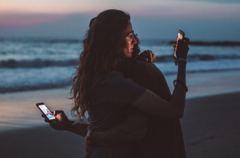 Umarmendes Paar mit Smartphone in der Hand