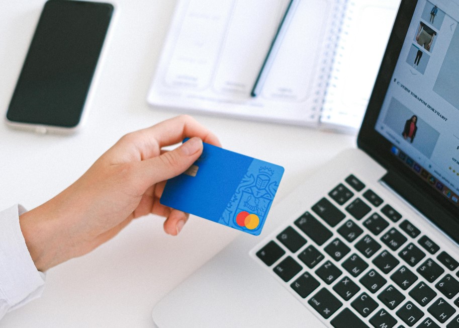 Mann mit Kreditkarte und Laptop als Symbolik für Online-Shopping