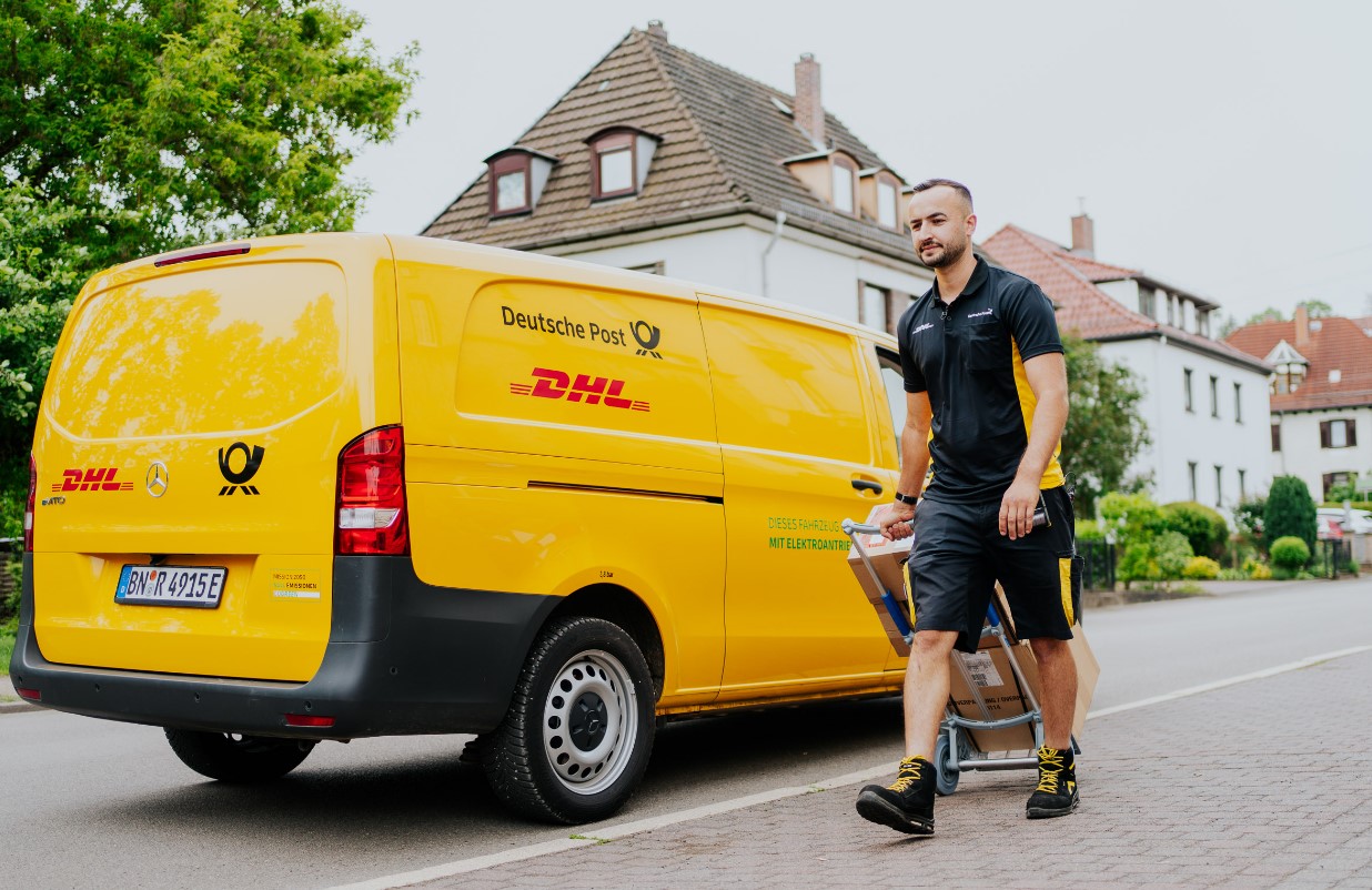 Zusteller von DHL vor einem Fahrzeug