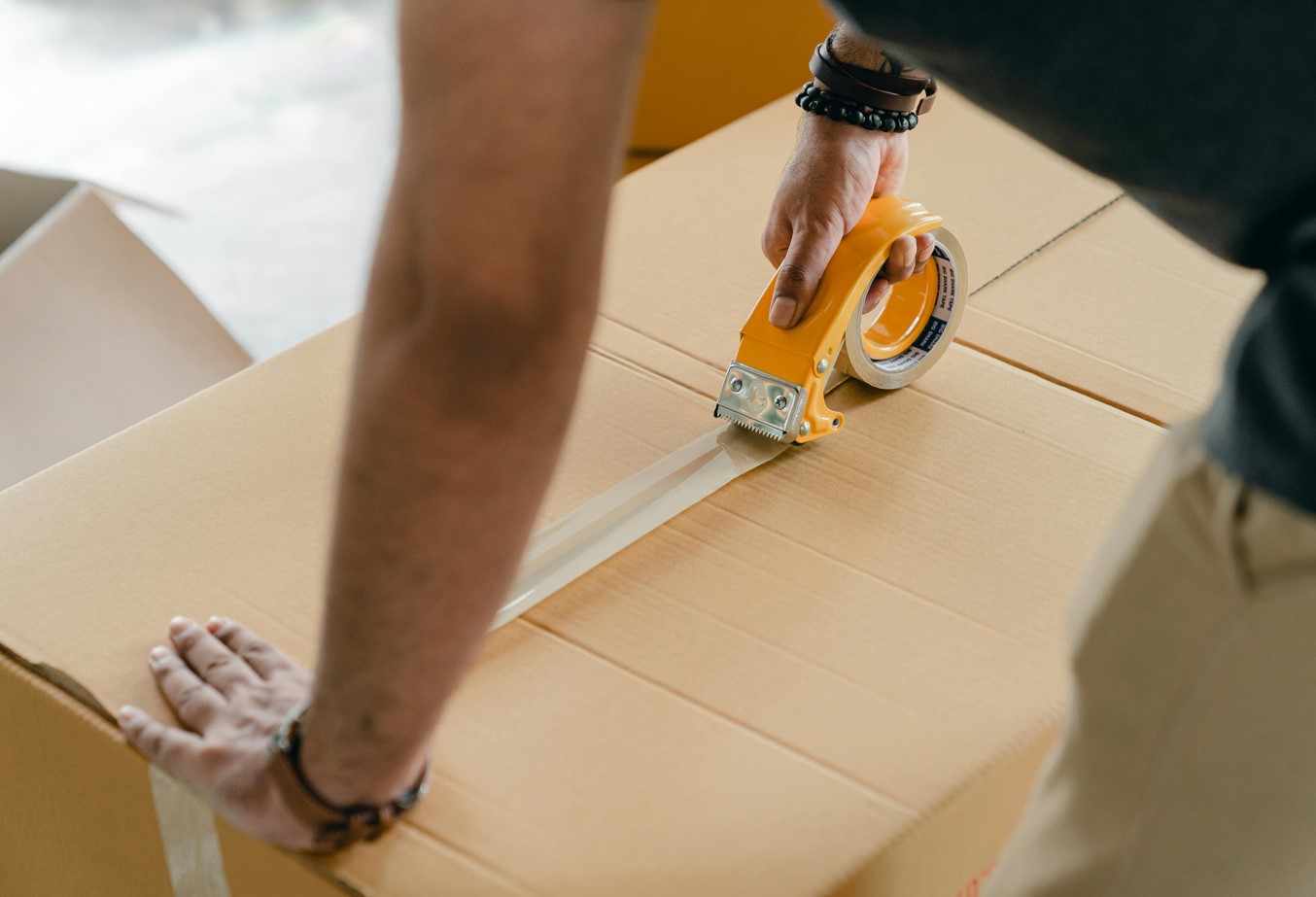 Mann beim Verschließen eines großen Sperrgut-Pakets