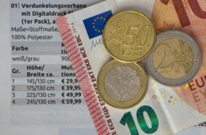 Euro Münzen und Geldschein vor einer Preistabelle