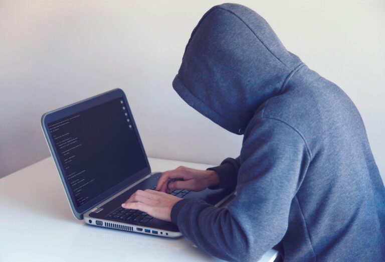 Mann mit Kapuzenpullover und Laptop als Hacker Symbol