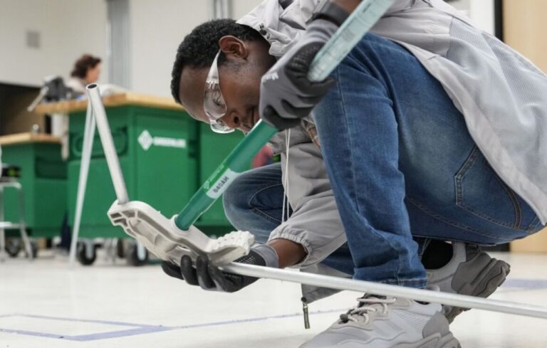 Schueler beom Pruefen eines Roboterarms