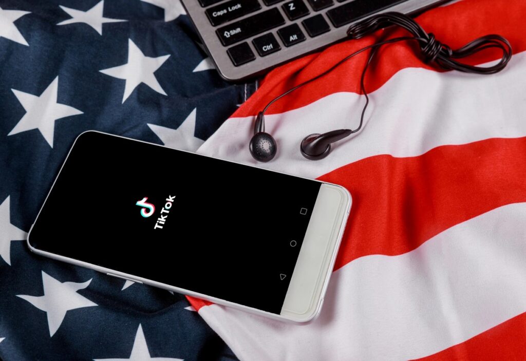 TikTok auf einem Smartphone vor einer USA Flagge