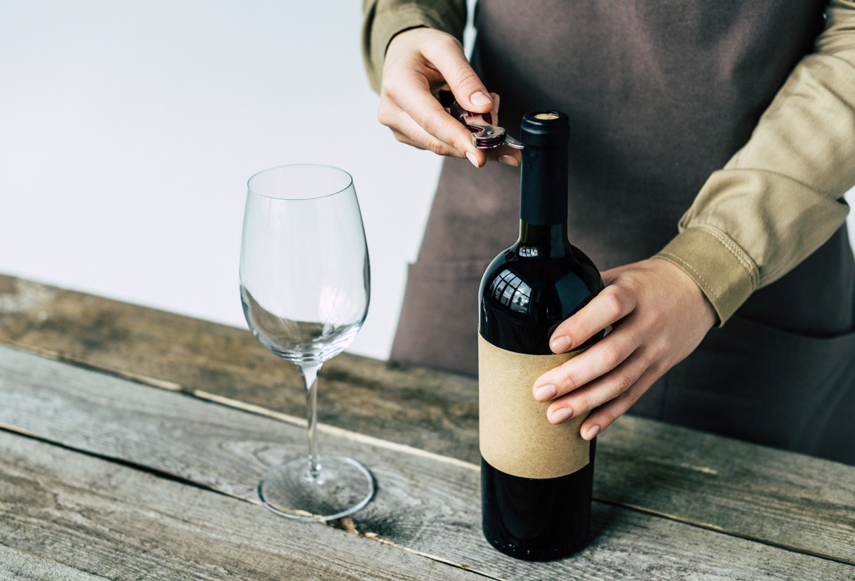 Mann beim Oeffnen einer Weinflasche