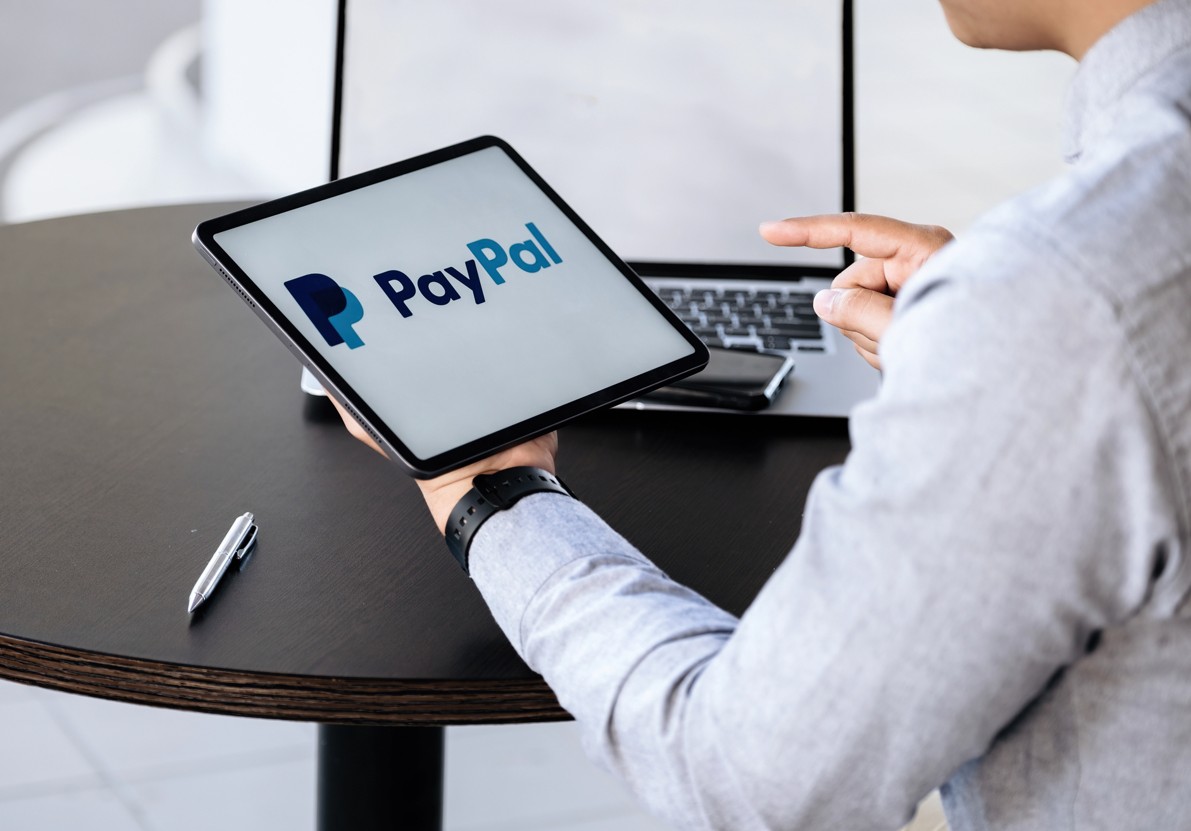 Mann mit Tablet mit PayPal Logo