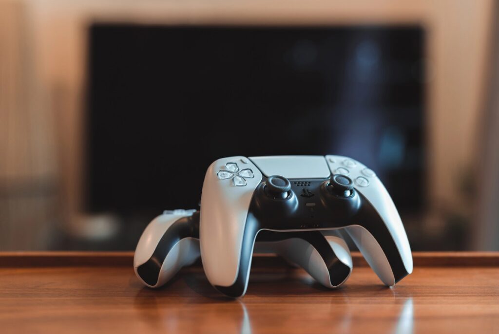 Zwei Playstation 5 Controller vor einem Fernseher