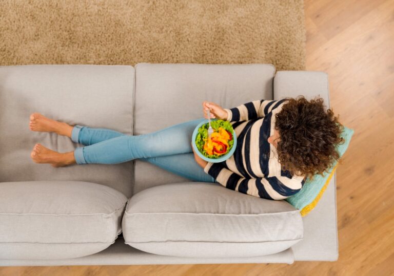 Frau beim Essen auf einem Sofa