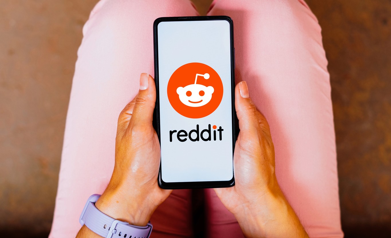 Frau mit Smartphone mit Reddit Logo