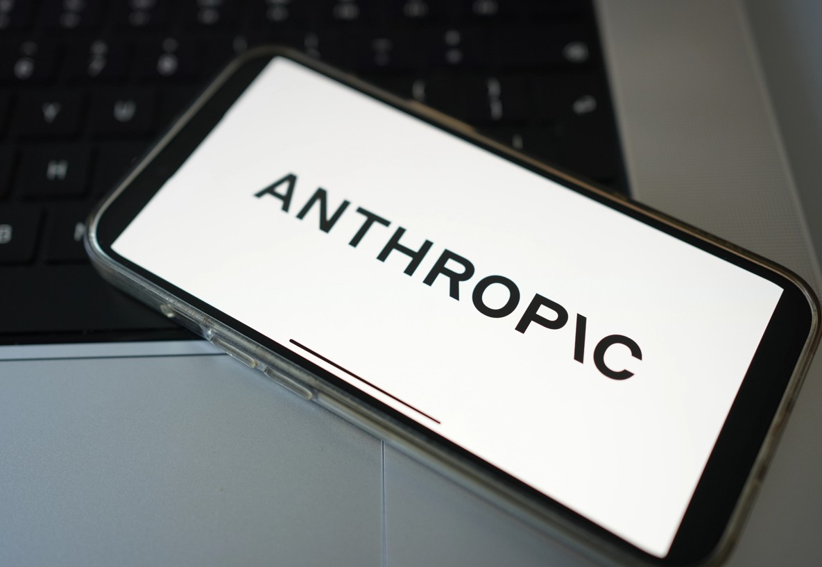 Anthropic Logo auf einem Smartphone vor einem Laptop
