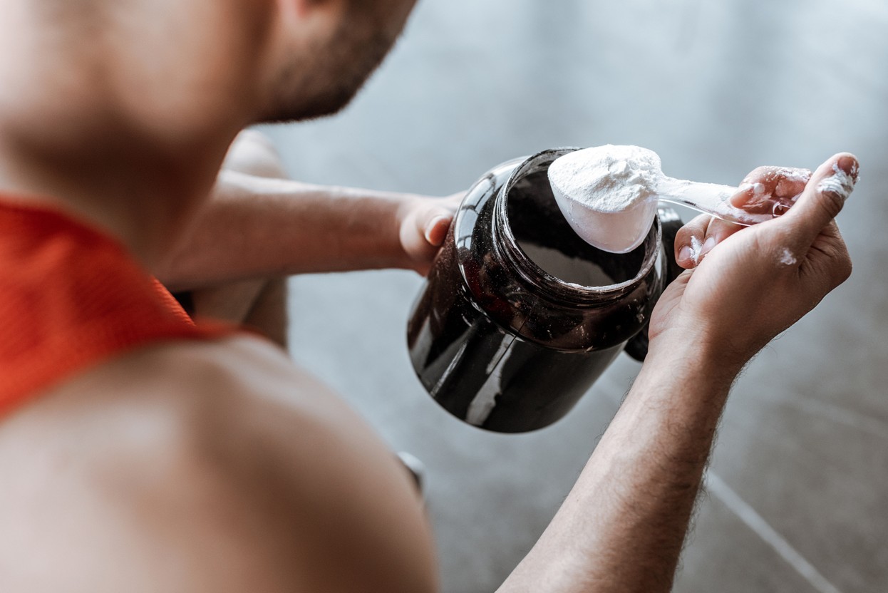 Mann in Sportbekleidung mit Proteinpulver