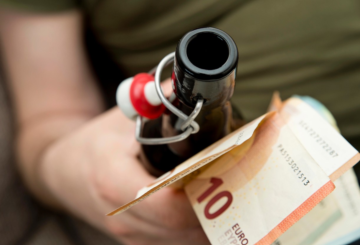 Mann mit Bierflasche und Euro Geldscheinen
