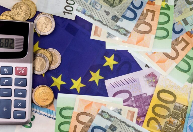 EU Flagge neben Taschenrechner und Euro Geldscheinen