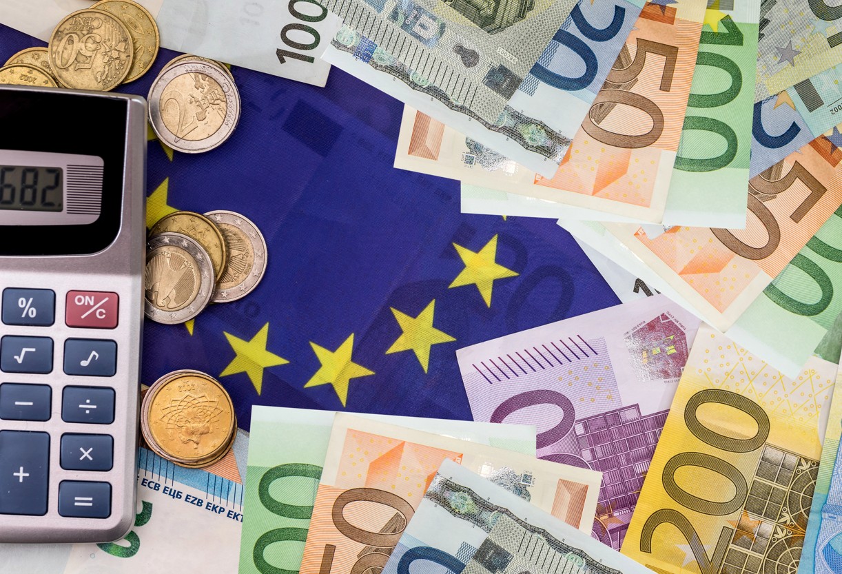 EU Flagge neben Taschenrechner und Euro Geldscheinen