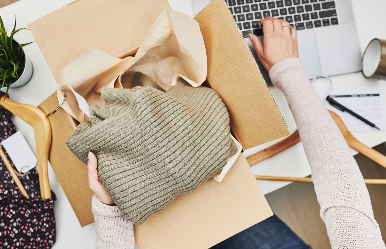 Frau beim Einpacken von Second Hand Bekleidung
