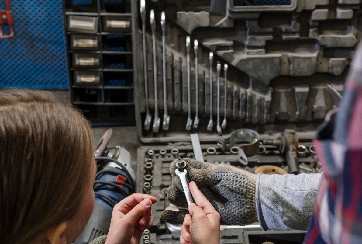 Maedchen vor Werkzeugkiste in Autowerkstatt