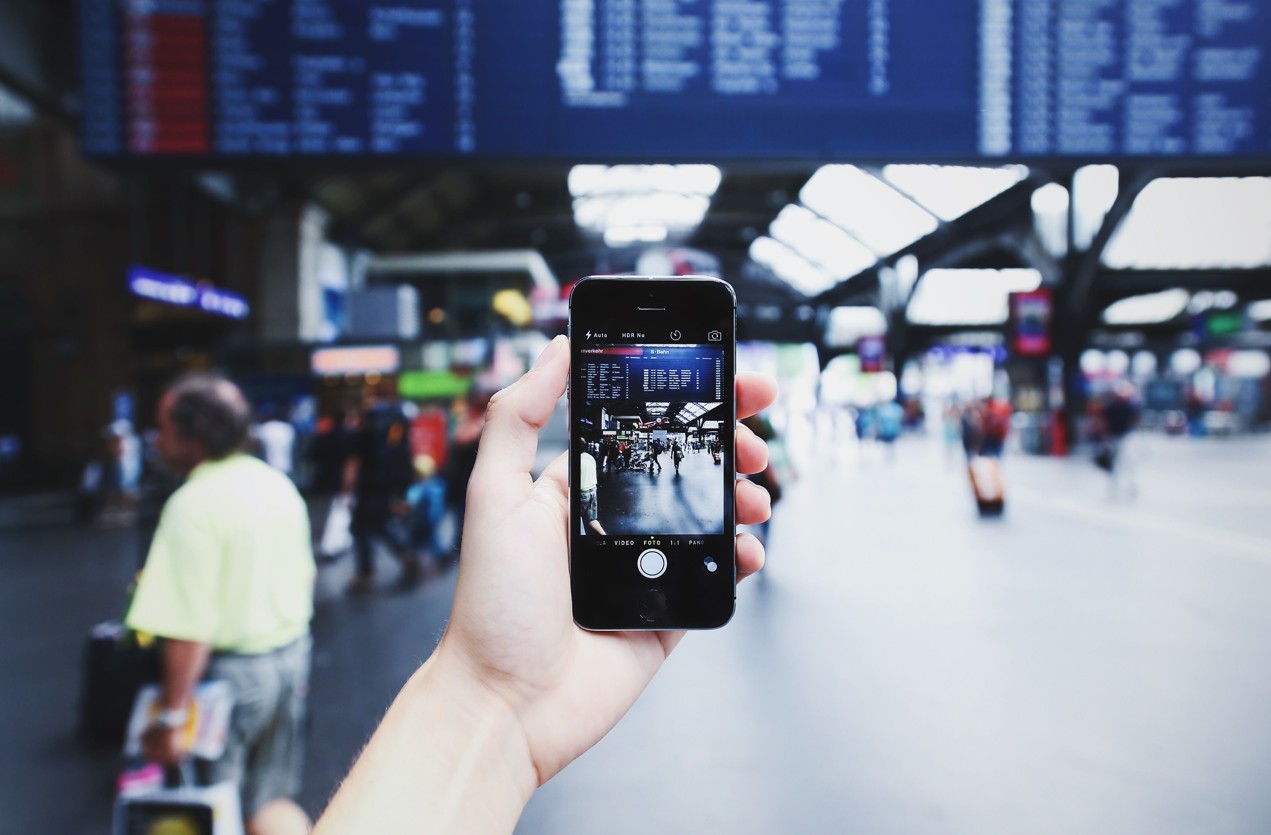 Smartphone vor einer Abflugtafel