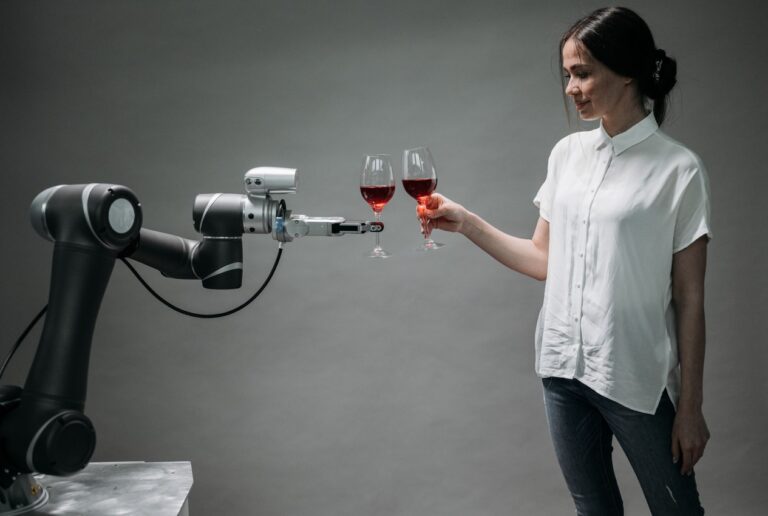 Frau gegenueber einem Roboterarm mit Weinglas