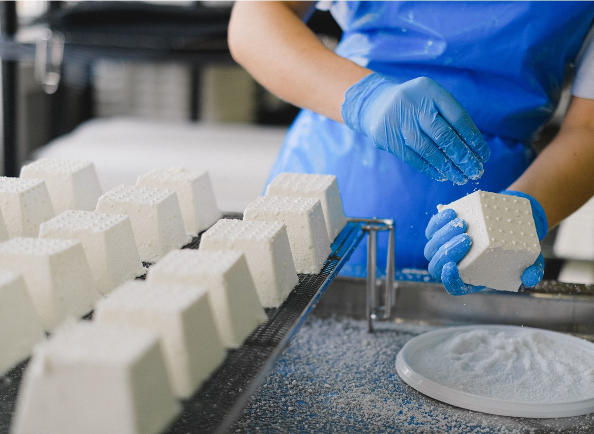 Arbeiterin beim Wuerzen von Kaese