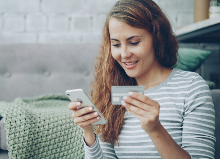 Junge Frau mit Smartphone und Kreditkarte