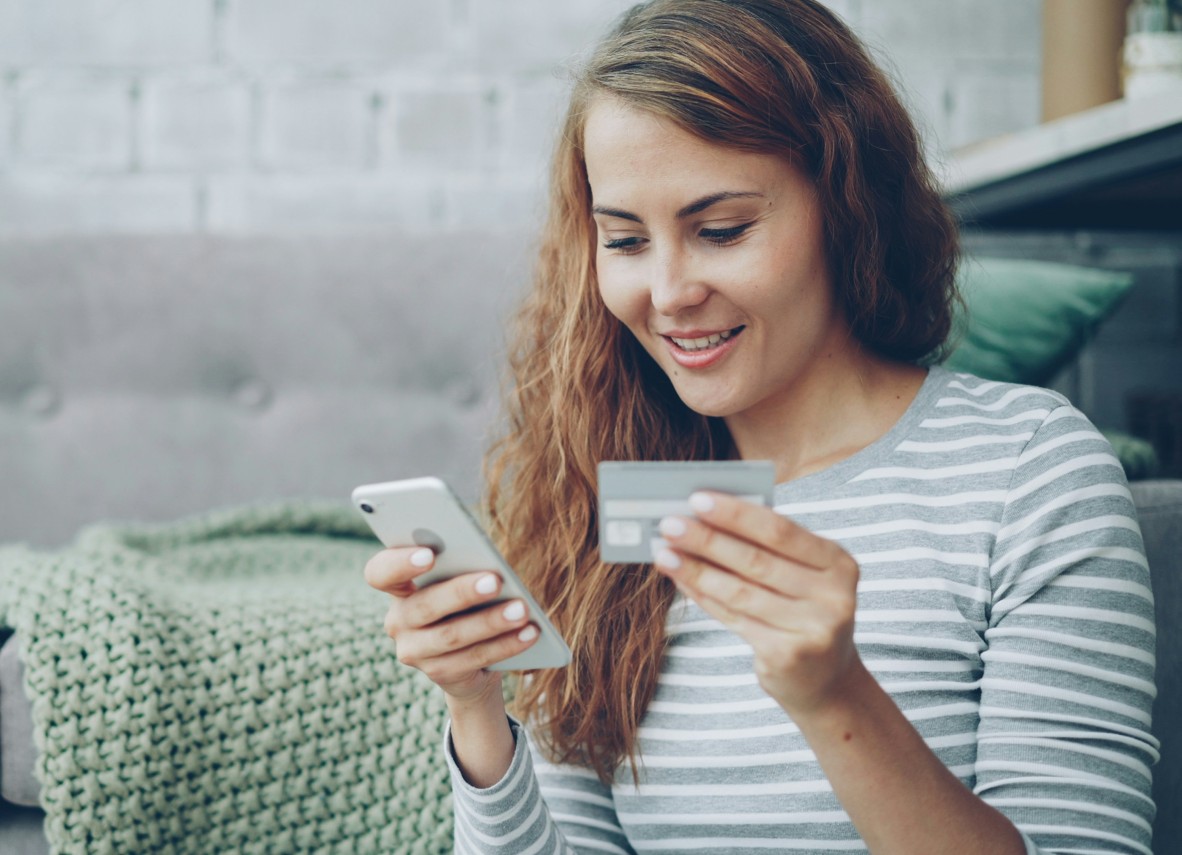Junge Frau mit Smartphone und Kreditkarte