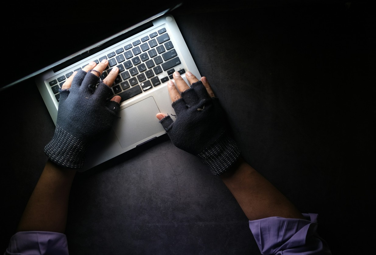 Mann mit Handschuhen an einem Laptop