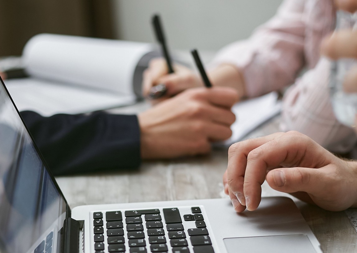 Mitarbeiter im Buero vor Laptop und Notizen